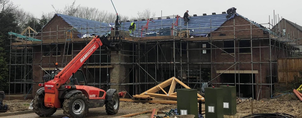 New-build house roof being tiled with scaffolding up